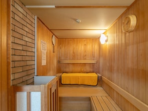 A sauna room with wooden walls, a bench, and a clock.