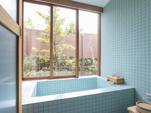 A bathroom with a bathtub, a window, and tiled walls.