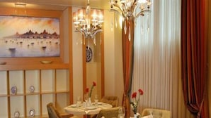 A dining area with round tables, chairs, and a chandelier. - Dareyn Konak Hotel (Istanbul)