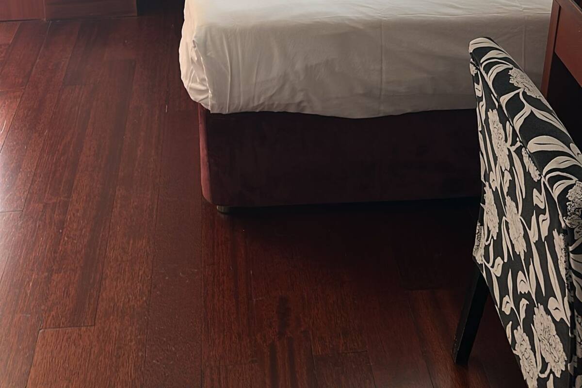 A hotel room with a bed, a nightstand, a lamp, and an air conditioning unit.