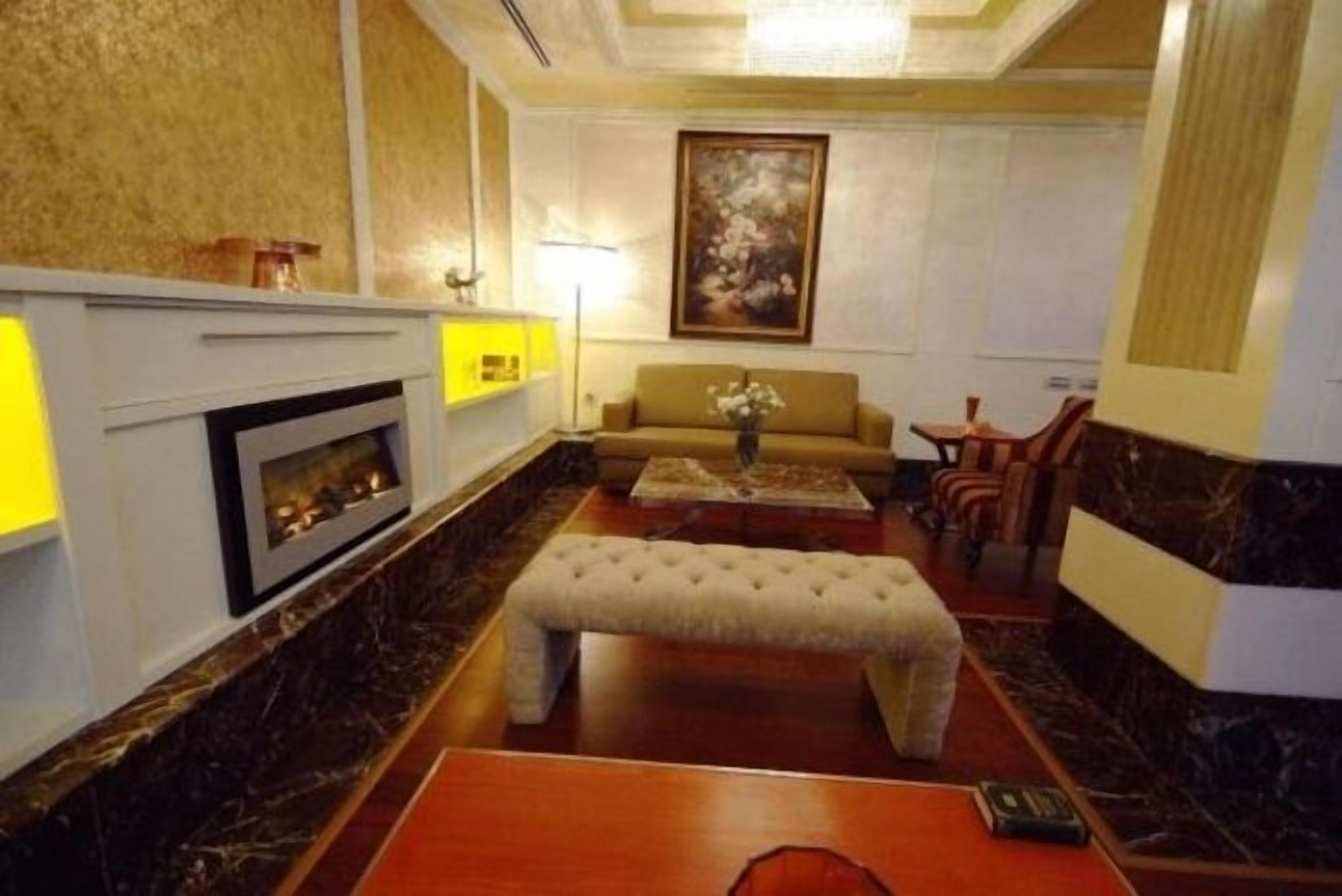 A spacious lobby with a marble fireplace, a sofa, a bench, and a small table with a vase.