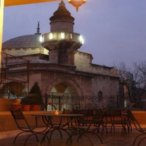 An outdoor seating area with tables and chairs, a fountain, and a mosque in the background. - Dareyn Konak Hotel (Istanbul)