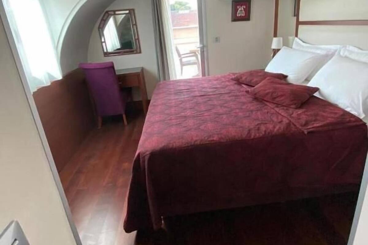 A bedroom with a bed, a desk, and a chair.