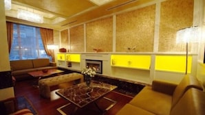 A modern living room with a sofa, ottoman, and coffee table. There is a fireplace and a yellow accent wall. - Dareyn Konak Hotel (Istanbul)
