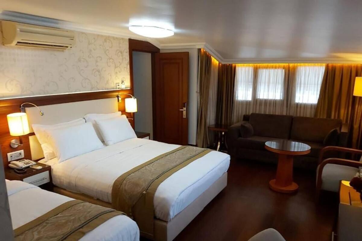 A hotel room with two beds, a sofa, a small table, and a lamp.