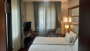 A hotel room with a bed, a TV, a chair, a desk, and a lamp. - Dareyn Konak Hotel (Istanbul)