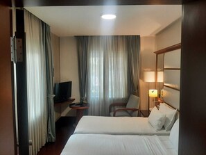 Habitación con 2 camas individuales | Edredón, minibar, caja de seguridad en la habitación y escritorio