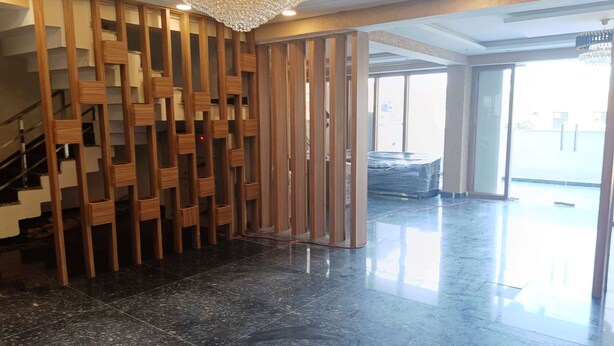 A lobby with a polished marble floor, a wooden partition, and a chandelier. - Pacific Inn City Center (Gurugram)