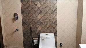 A bathroom with a toilet, a shower, and a hand dryer. - Pacific Inn City Center (Gurugram)