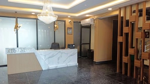 A reception area with a marble counter, a chandelier, and a wooden partition. - Pacific Inn City Center (Gurugram)