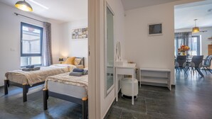 Ein modernes Schlafzimmer mit zwei Betten, einem Nachttisch, einem Spiegel und einem Fenster mit Vorhängen.