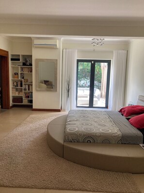 A bedroom with a large bed, a built-in wardrobe, a mirror, and a view through a sliding glass door. - Villa Contemporaine - Côte Ouest (Rivière Noire)