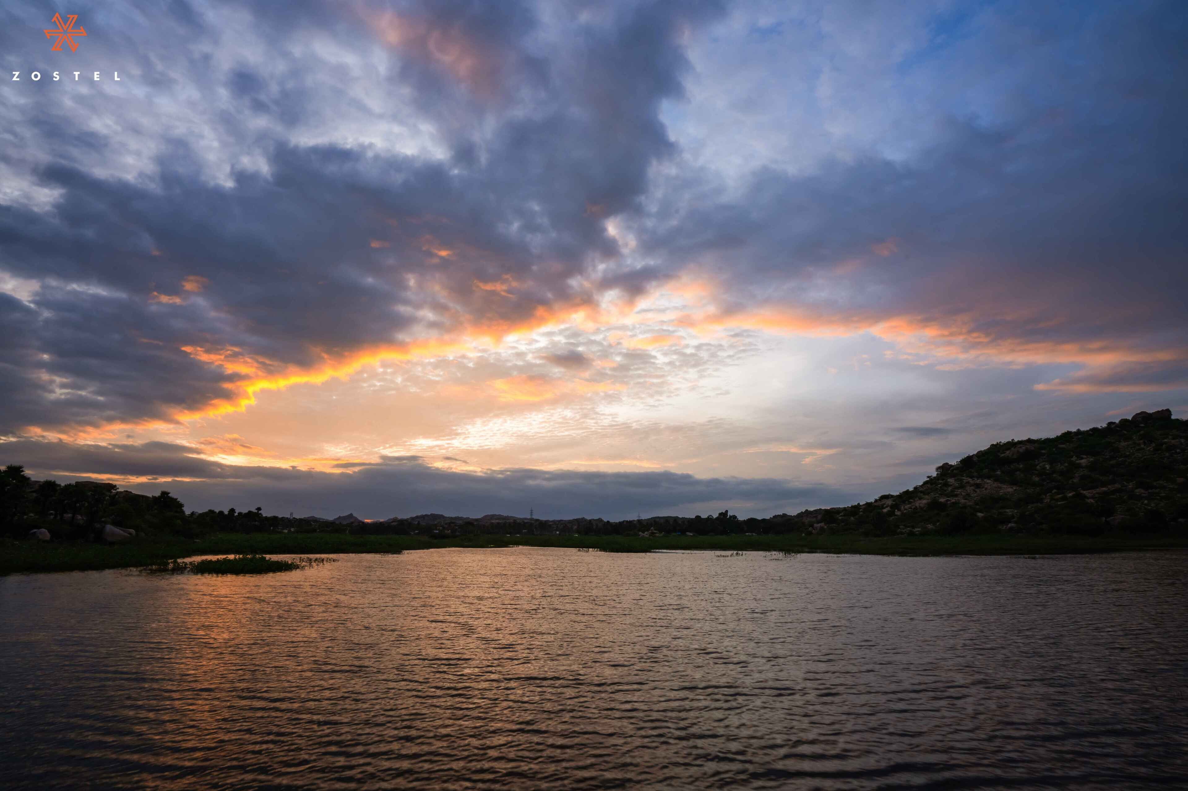 Un atardecer sobre un lago tranquilo con un paisaje montañoso al fondo.