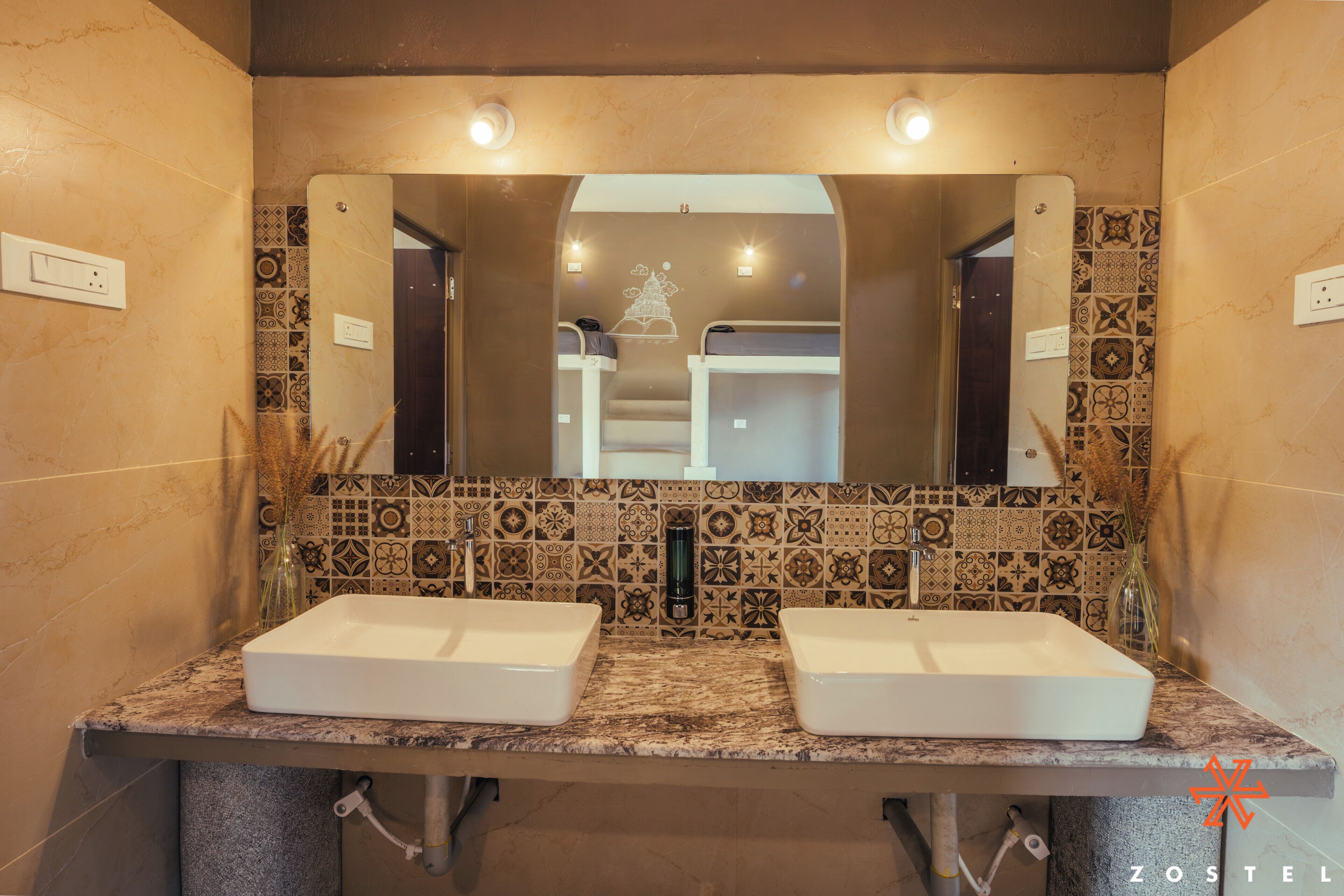 Une salle de bain avec deux lavabos, un miroir et des carreaux décorés.