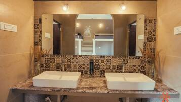 Une salle de bain avec deux lavabos, un miroir et des carreaux décorés.