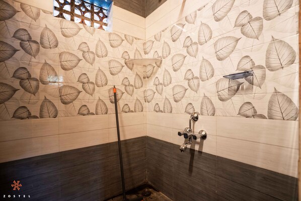 A bathroom with a leaf-patterned wall, a shower area, and a dark wooden floor. - Zostel Hampi (Gangavathi) (Gangavathi)