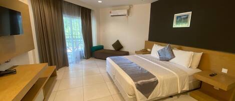 A hotel room with a bed, a TV, a desk, a chair, and a window with curtains.