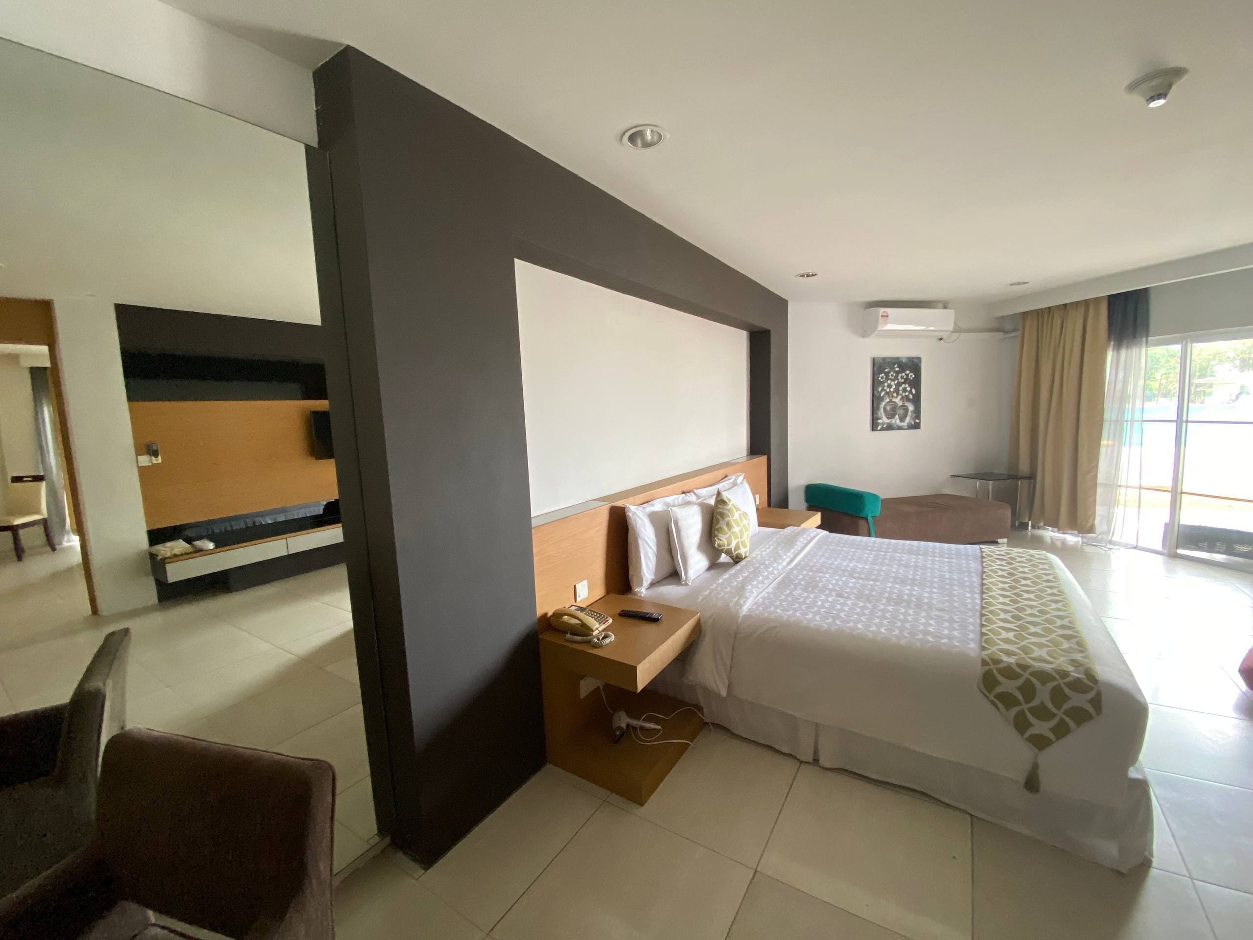 Una habitación de hotel moderna con una cama grande, un escritorio con teléfono, una silla y vistas al exterior.