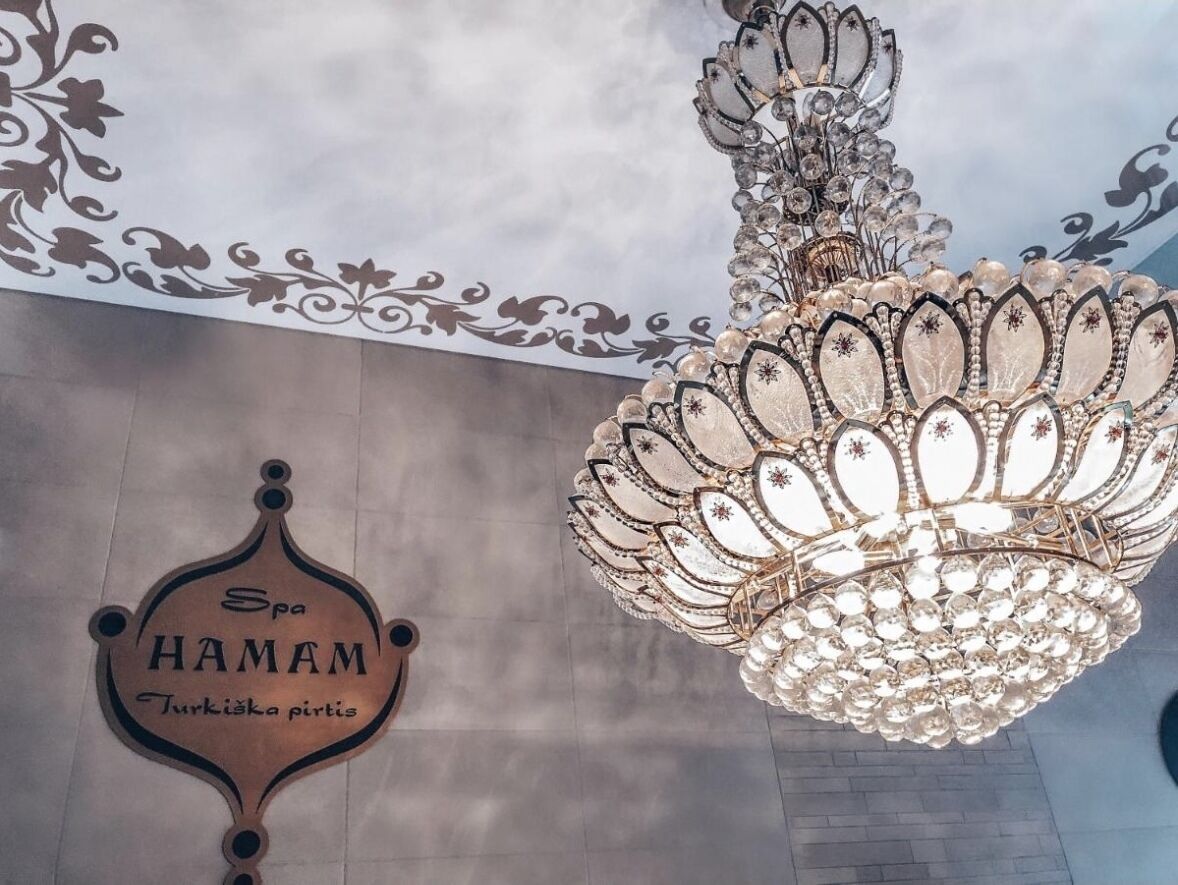 Un candelabro con diseño floral y un cartel que dice "Spa HAMAM" con texto en turco.