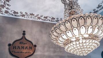 Un candelabro con diseño floral y un cartel que dice "Spa HAMAM" con texto en turco.