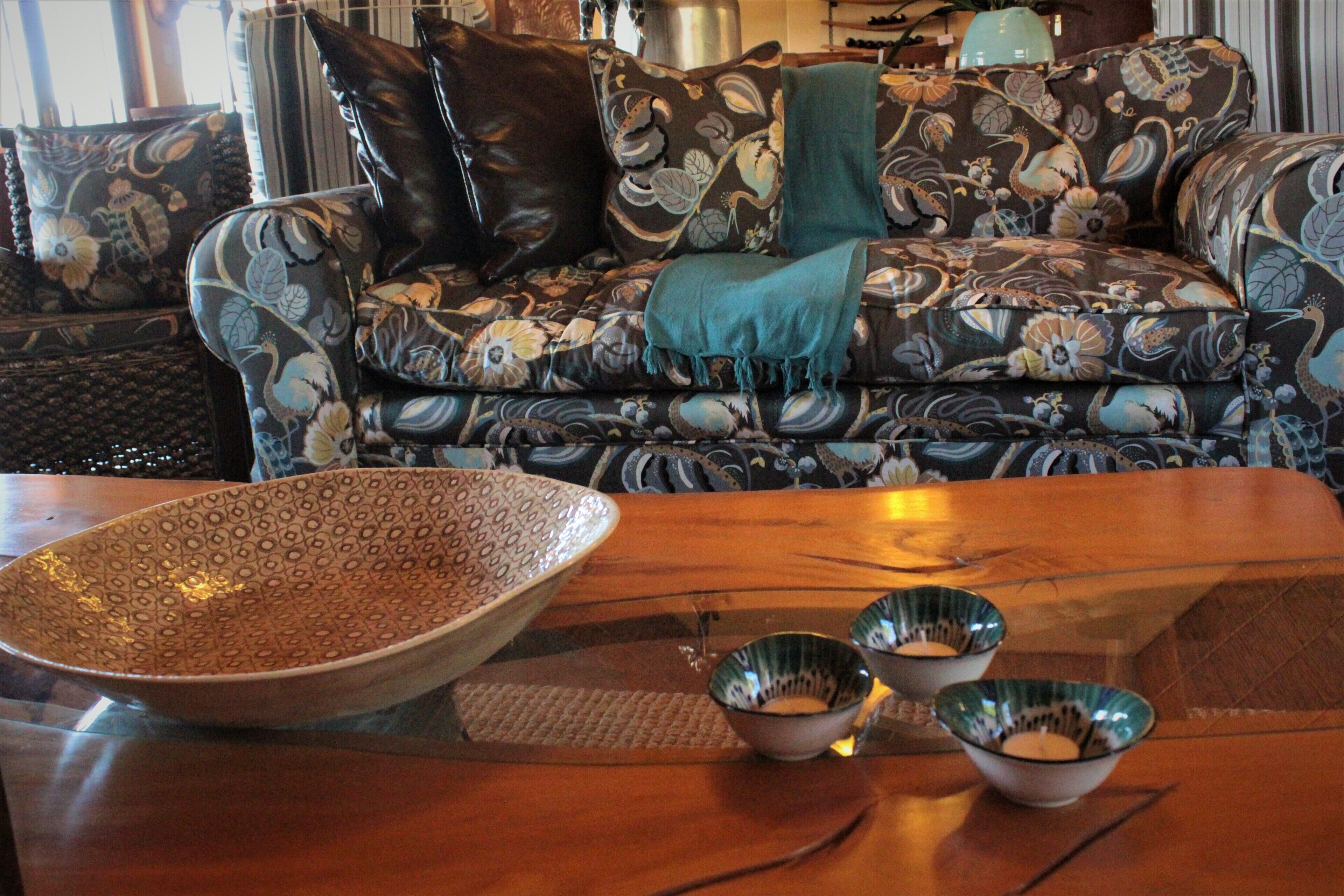 A living room with a patterned sofa, a large decorative bowl, and two smaller bowls on a wooden coffee table.