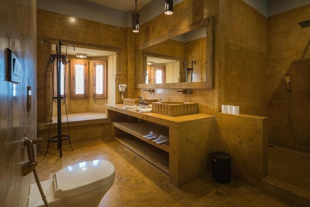 A bathroom with a large mirror, a sink, a toilet, and a shower area.