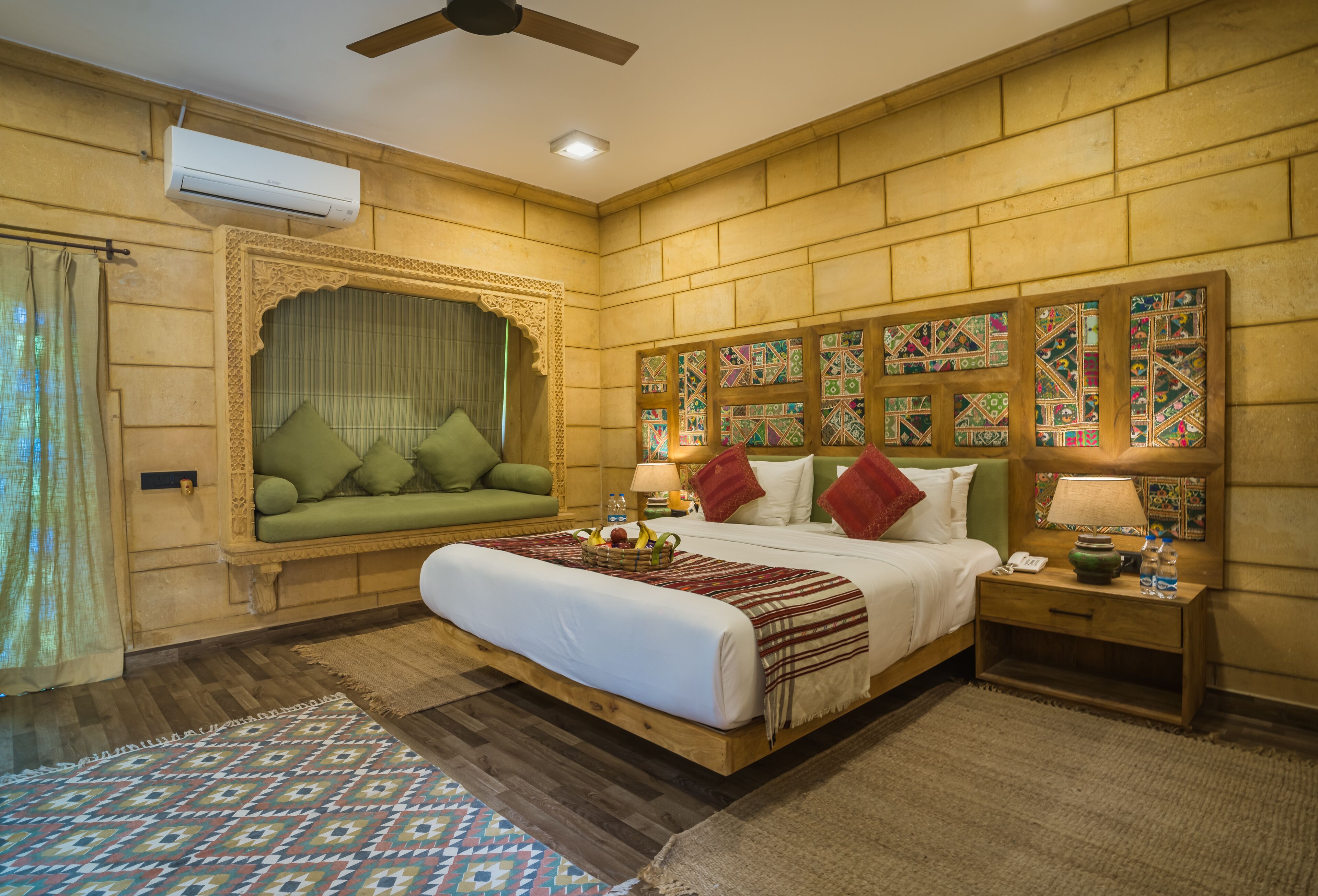 A room with a large bed, a sofa, a nightstand, and a decorative wall.
