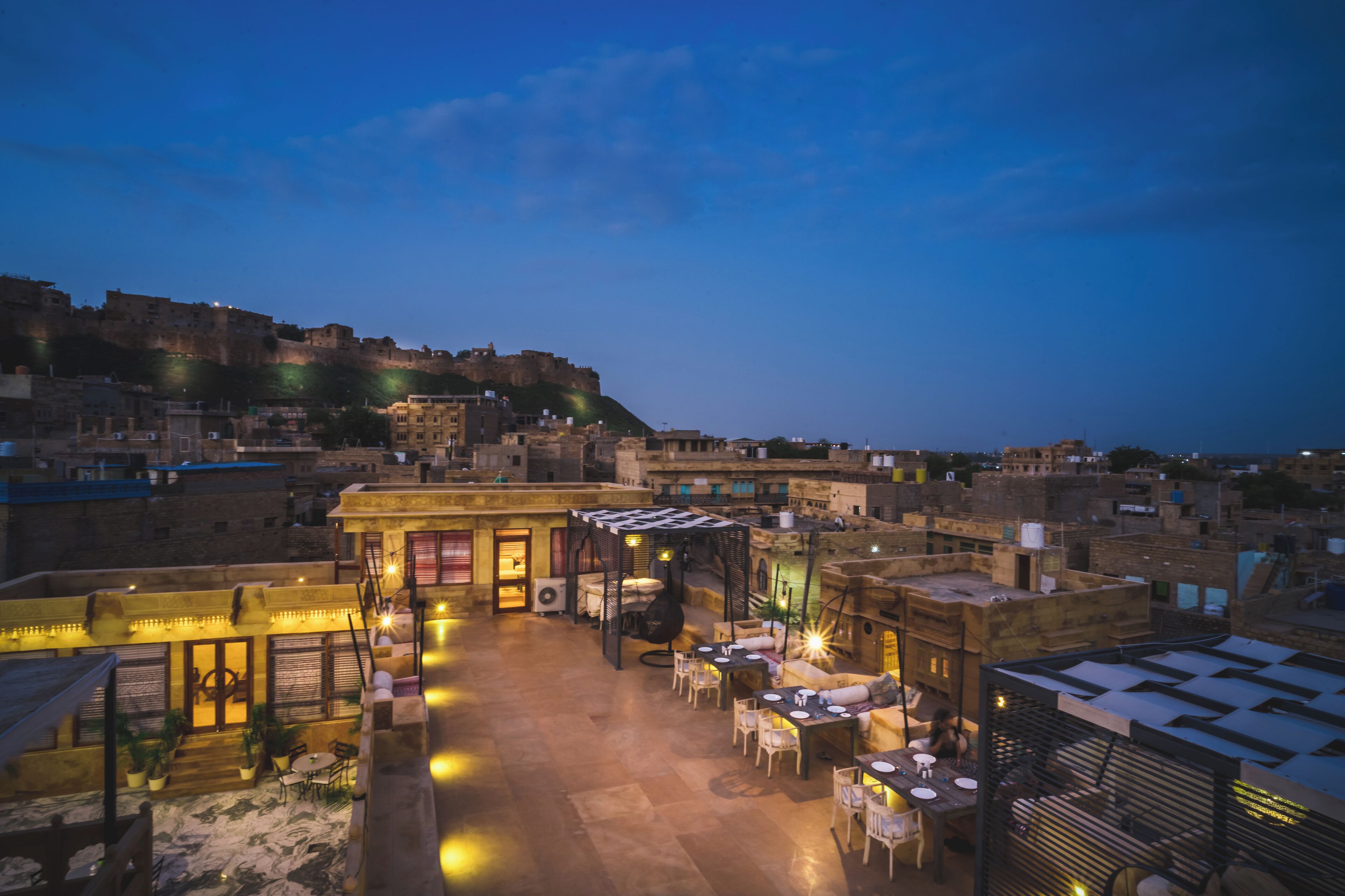 Une terrasse sur le toit avec des sièges en plein air, une vue sur un bâtiment historique en arrière-plan et un ciel dégagé.