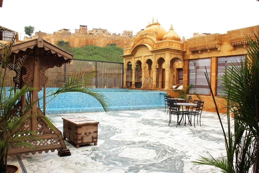 A courtyard with a pool, outdoor seating, and a view of a historic fort in the background.