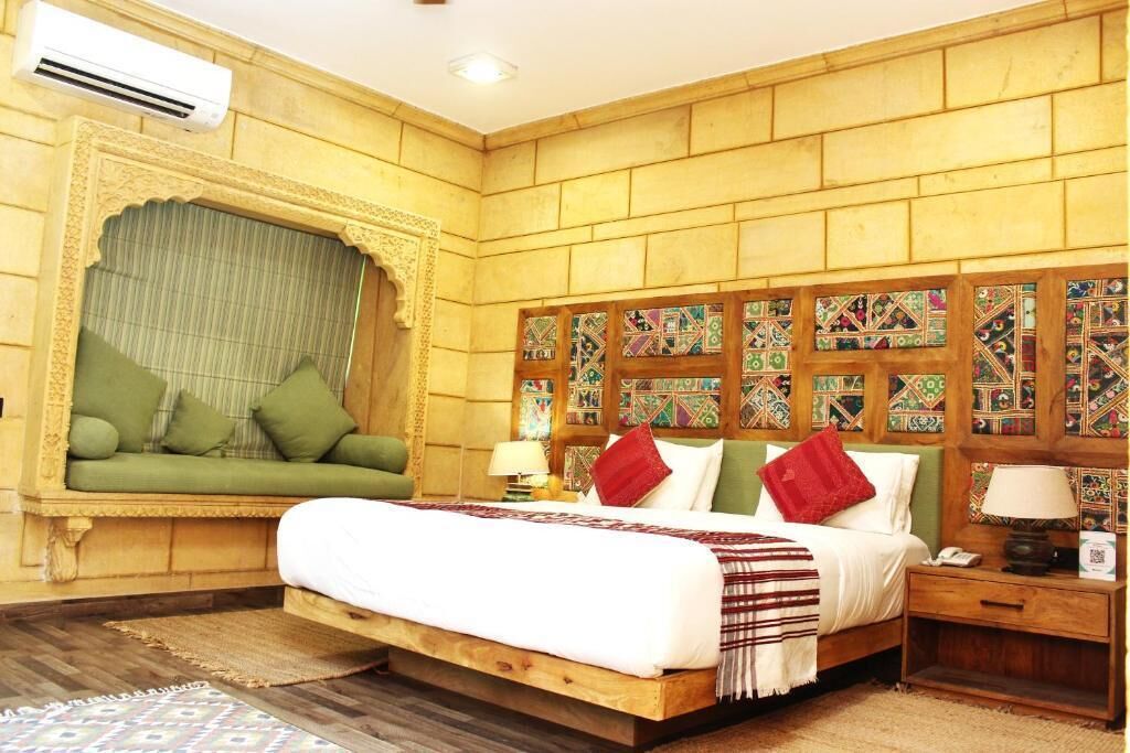 Une chambre au décor traditionnel, avec un lit, un canapé vert, des motifs décoratifs sur les murs et une tête de lit en bois.