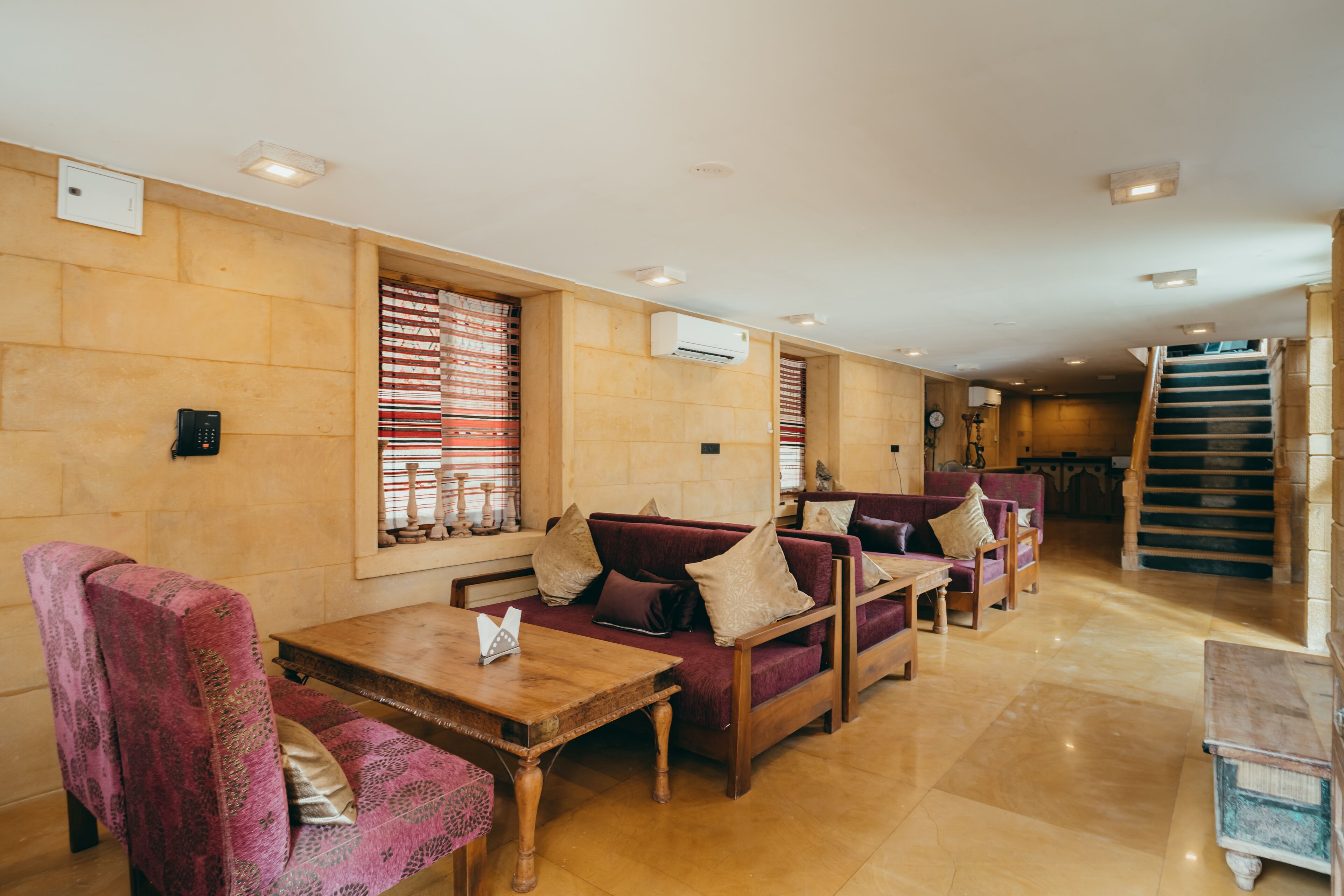 A hotel lobby with seating areas, a staircase, and a wooden table.