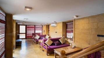 A hotel lobby with a wooden floor, purple sofas with cushions, a wooden table, and a staircase.