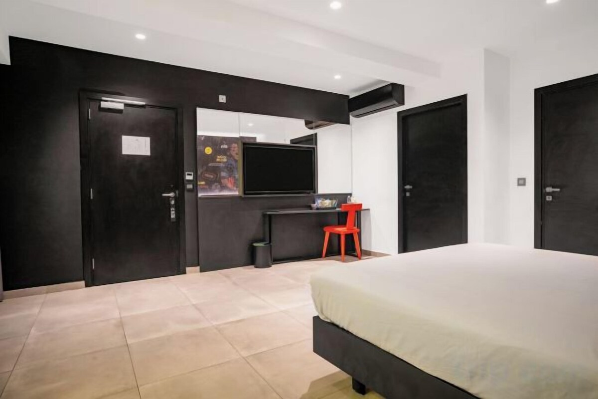 A modern bedroom with a bed, a desk, a chair, and a television.