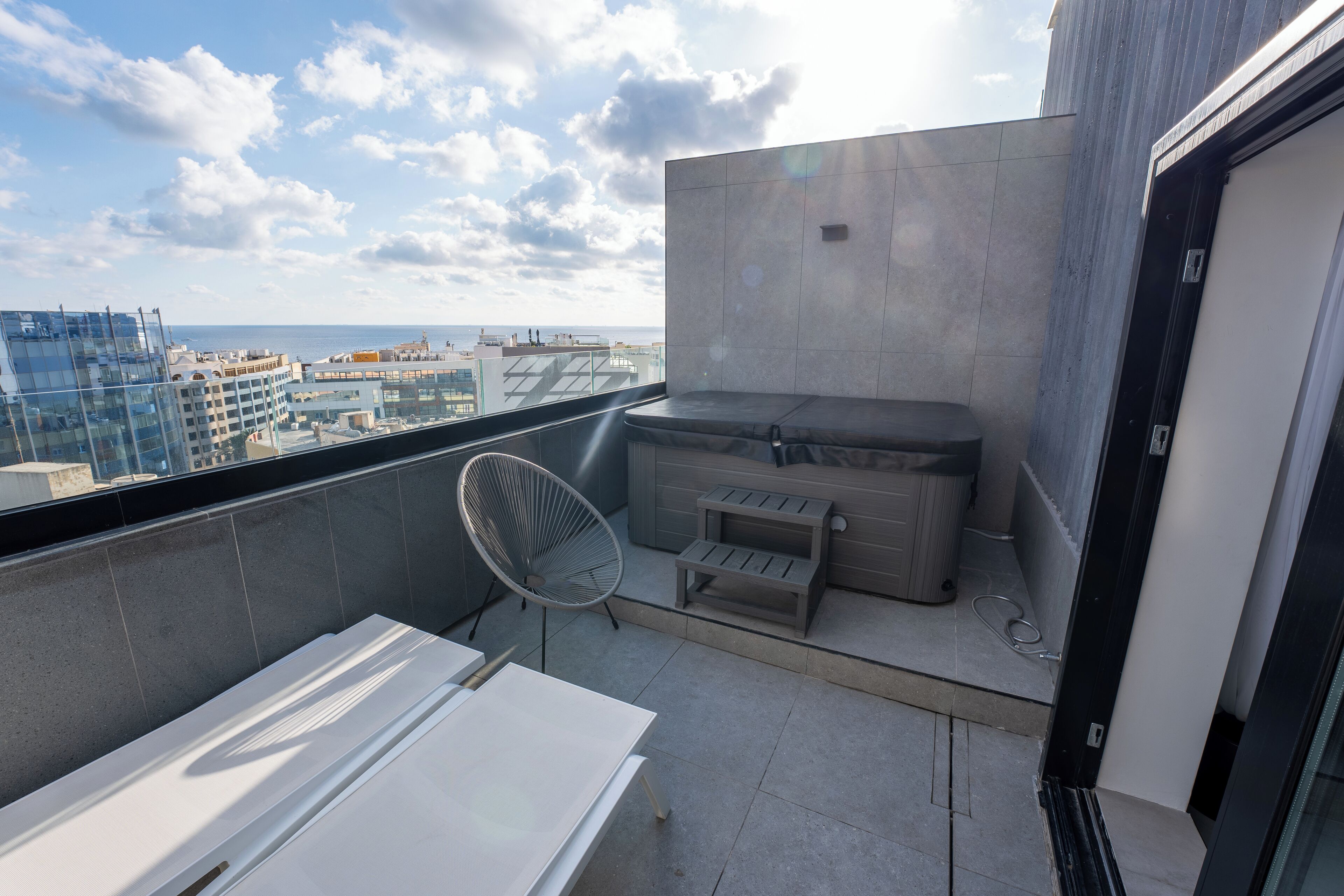 A balcony with a white table, a chair, and a built-in hot tub.
