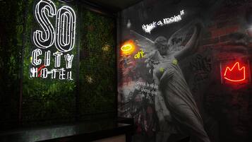Une enseigne au néon indiquant « SO CITY HOTEL » et une fresque représentant un ange et des graffitis.