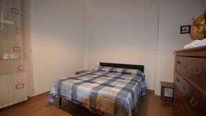 Un dormitorio con cama, cómoda y una mesita.