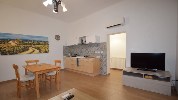 Un espacio habitable compacto con comedor, kitchenette y televisor.