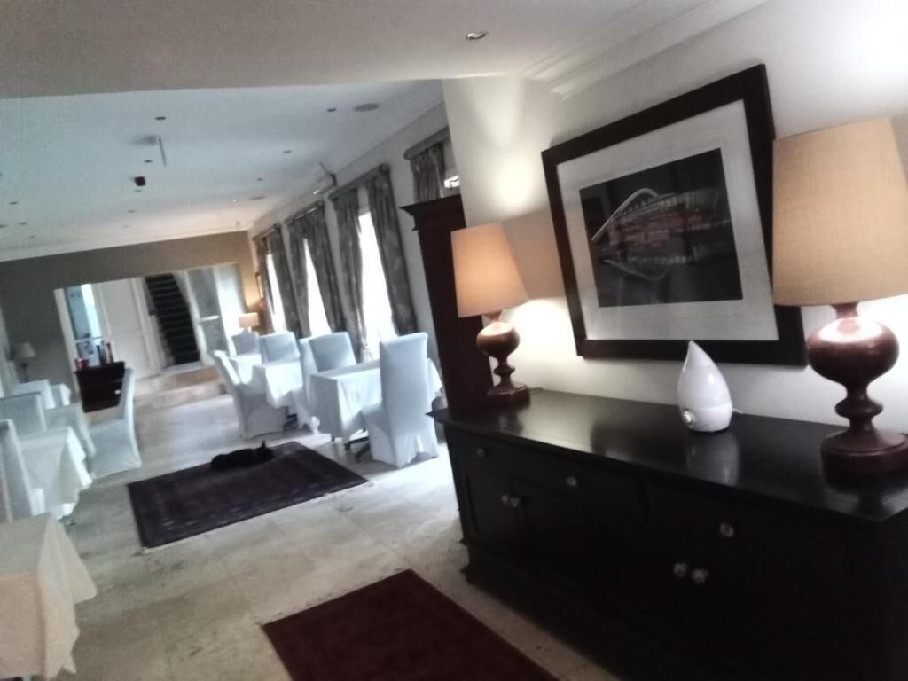 A spacious living room with a large window, a dark wooden cabinet, and a framed picture on the wall.