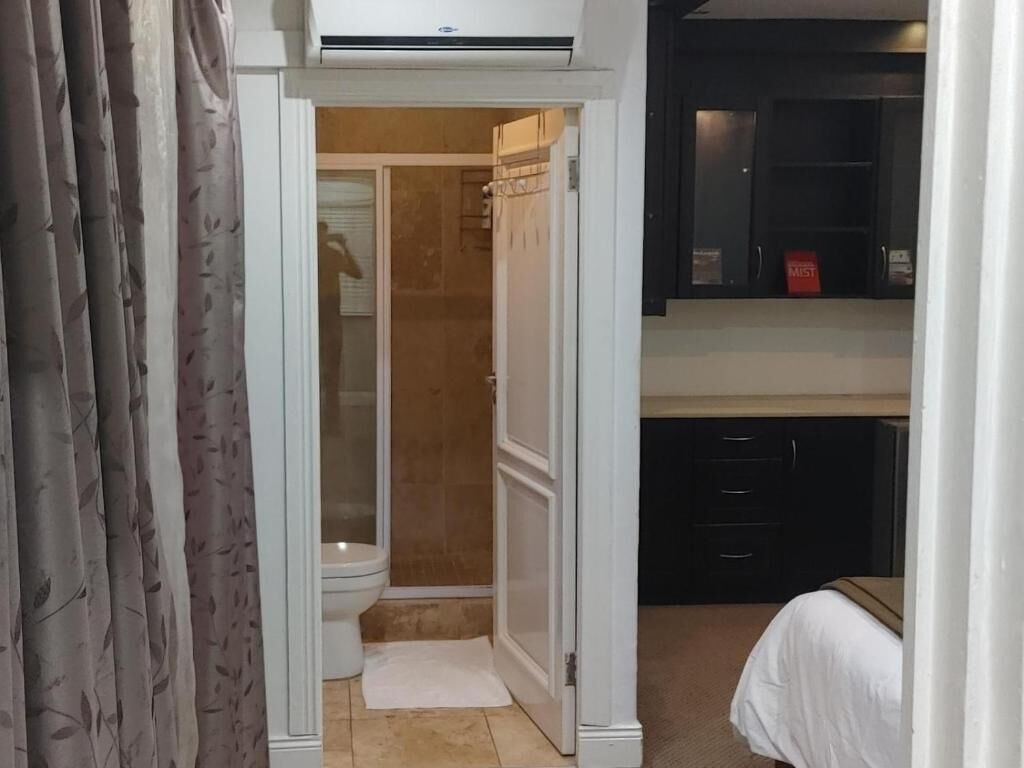 A bathroom with a toilet, shower, and a cabinet with a red sign.