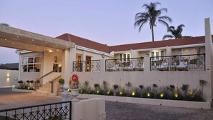 A modern house with a stone facade, a red-tiled roof, and a well-lit entrance. - 131 on Herbert Baker Boutique Hotel (Pretoria)