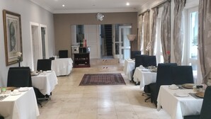 A spacious dining area with multiple tables and chairs, a central rug, and a staircase leading to an upper level. - 131 on Herbert Baker Boutique Hotel (Pretoria)