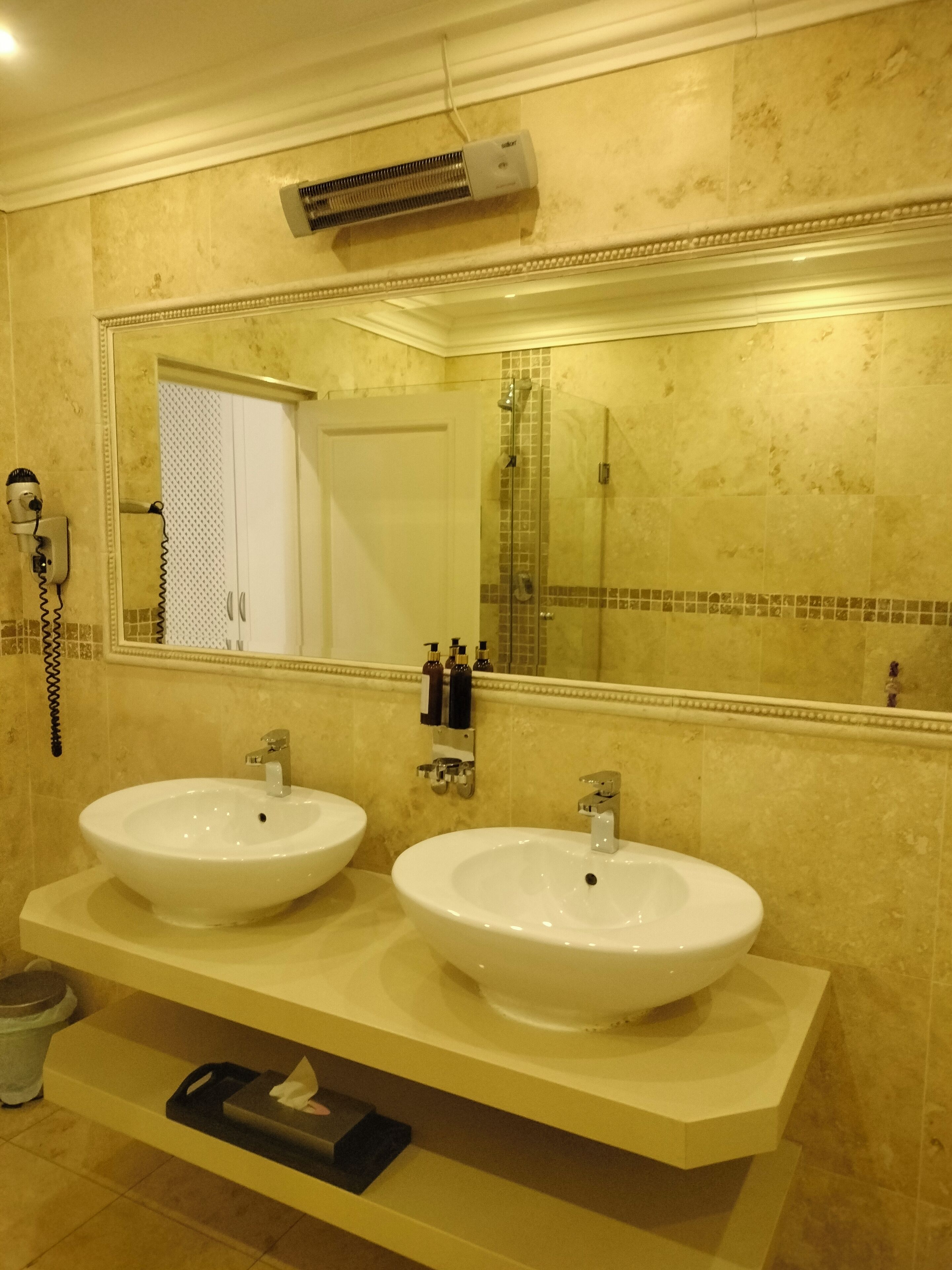 A bathroom with two sinks, a large mirror, and a shower.
