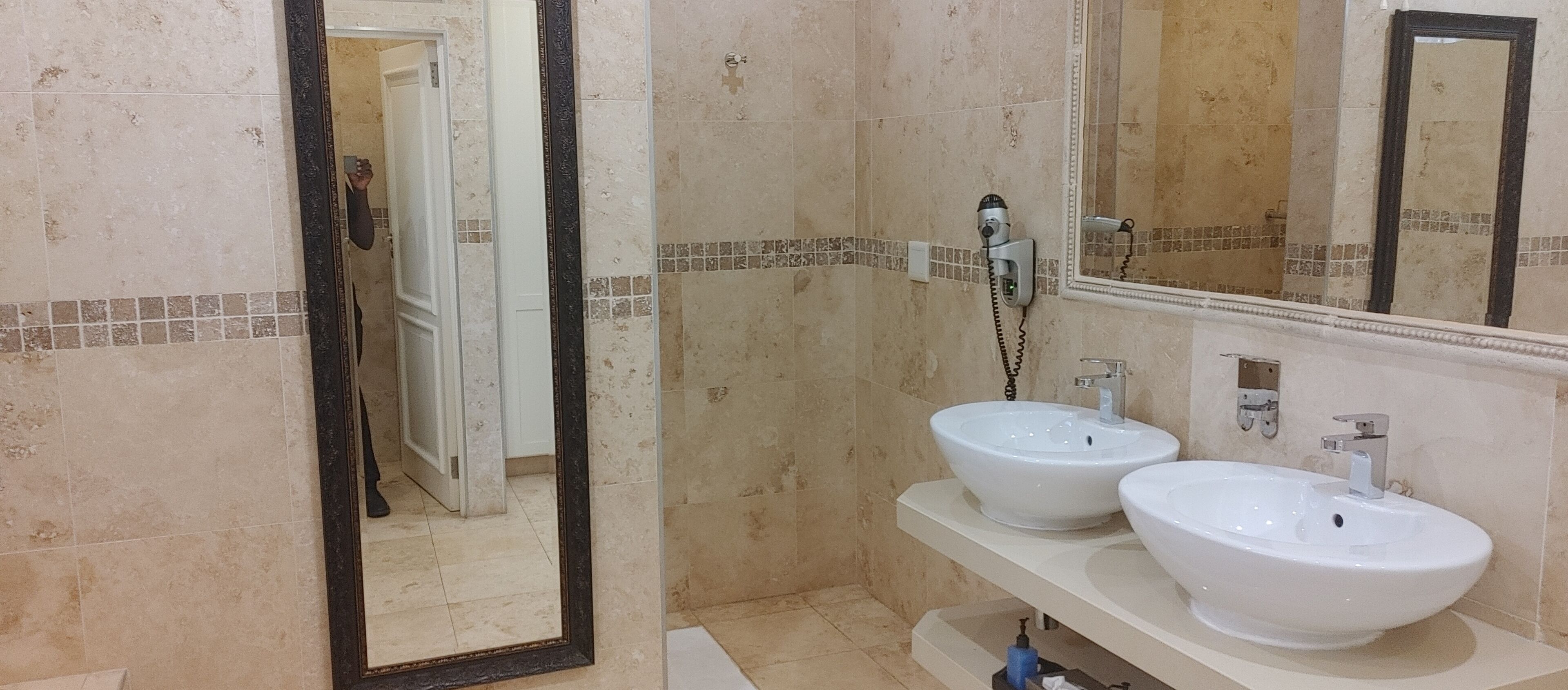 Un baño con dos lavamanos blancos, un espejo y una ducha.