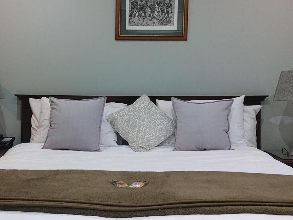 A neatly made bed with a brown throw blanket and patterned pillows.