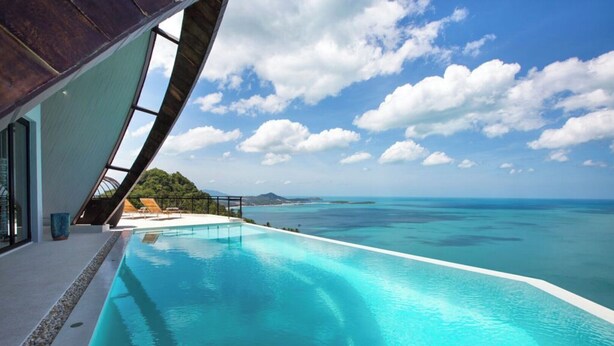 Ein moderner Infinity-Pool mit freiem Blick auf den Ozean und eine tropische Landschaft.