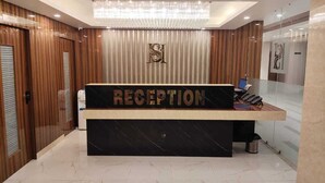 A reception area with a marble floor, a reception desk, a chandelier, and wooden paneling on the walls.