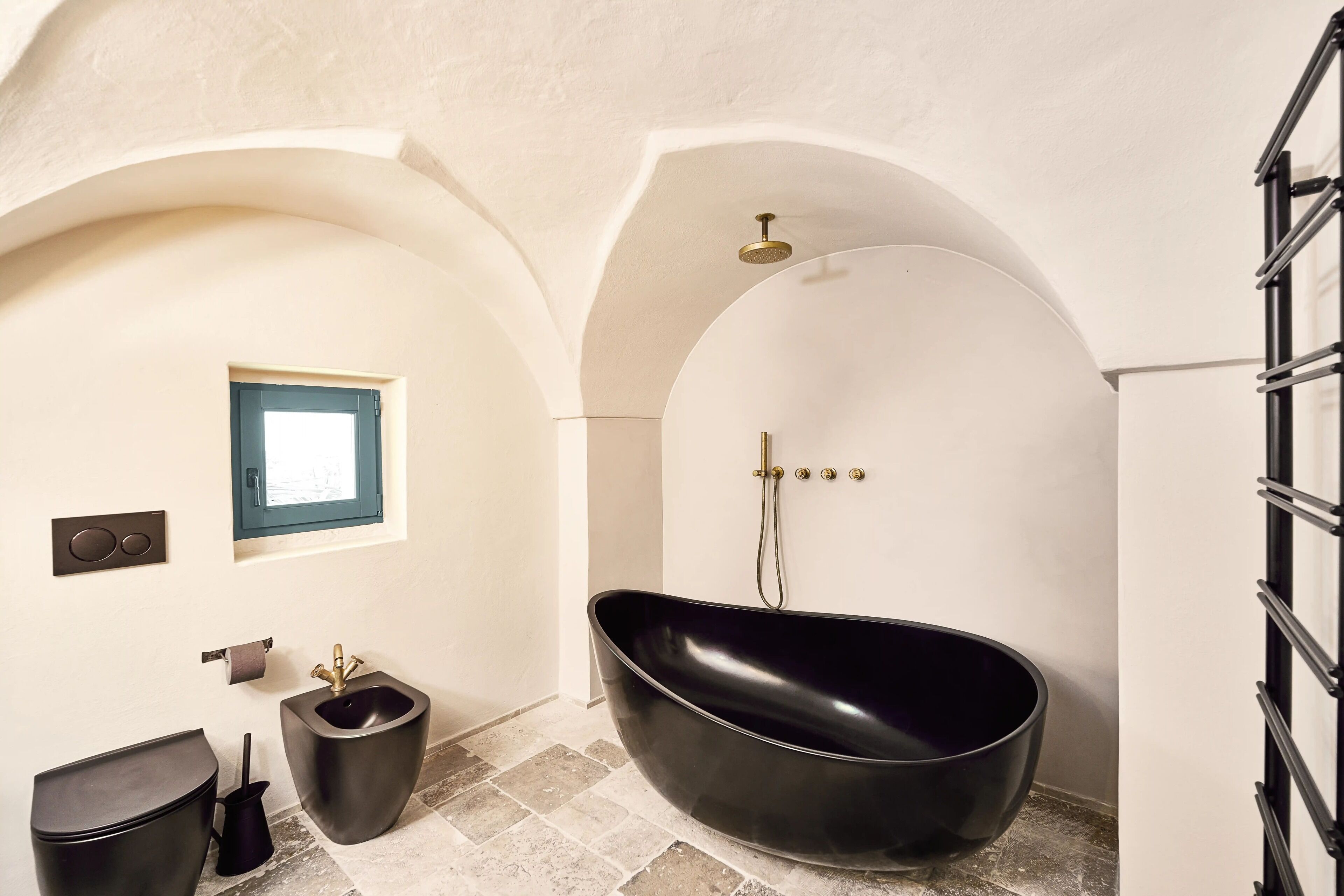 A modern bathroom with a freestanding bathtub, a window, and a towel rack.
