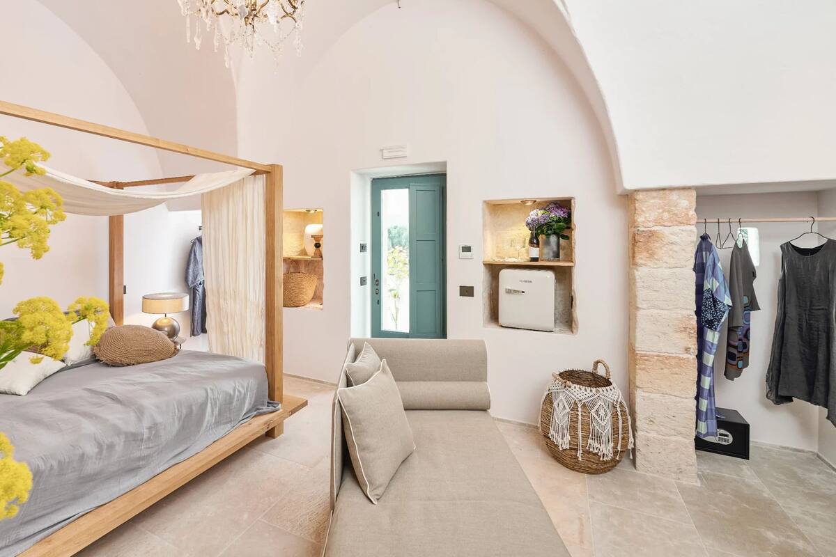 A bedroom with a bed, bedside table, lamp, and a hanging light fixture.