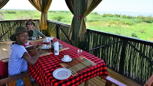 Mesa con platos, cubiertos y una botella de agua, con vistas a un paisaje cubierto de hierba.