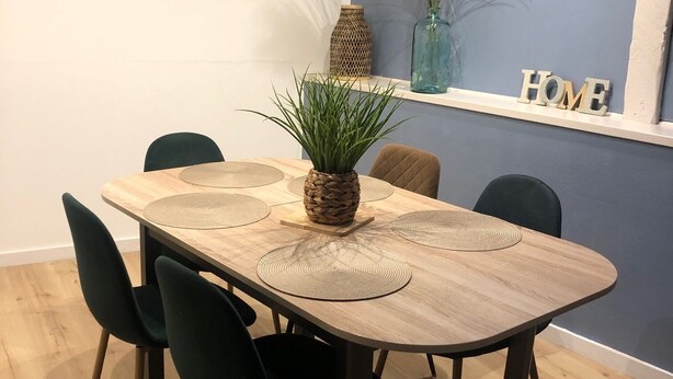 A dining area with a wooden table, black chairs, a pineapple centerpiece, and decorative items on the wall.